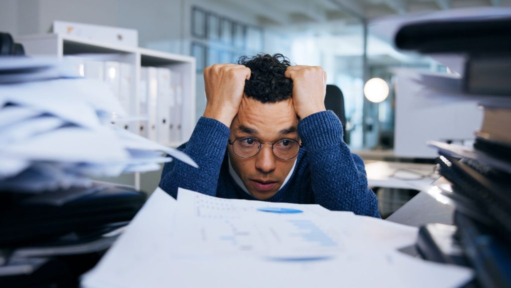 Man looking stressed at piles of documents